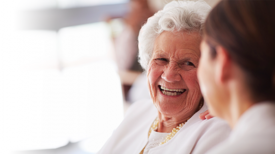 A smiling care home resident talking to a family member
