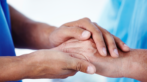 A carer holding a patient's hand.