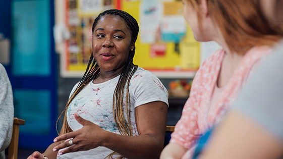 A side view of women having a conversation sitting in a community centre. 