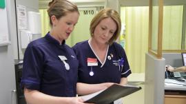2 nurses looking at a document in a folder