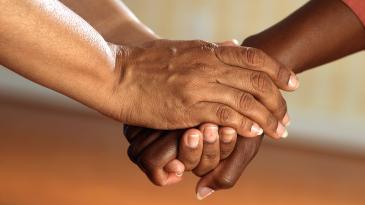 One person's hand being held affectionately by both hands of another person